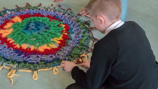 Young male pupil weaving a mat in crafts session